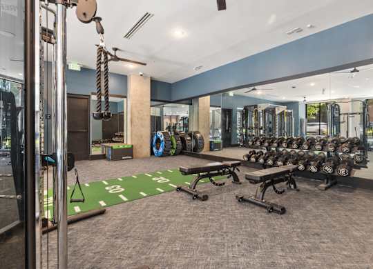 A gym with a variety of equipment including weights and a bench.