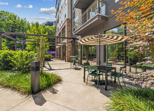 A patio with a table and chairs under a striped umbrella.