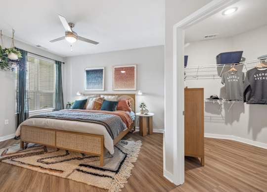 A bedroom with a bed, a rug, a ceiling fan and a wardrobe.