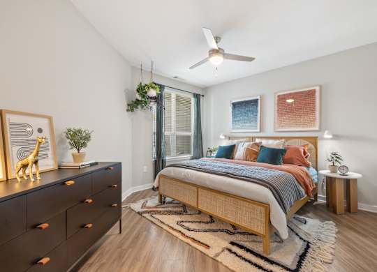 A bedroom with a bed, dresser, and ceiling fan.
