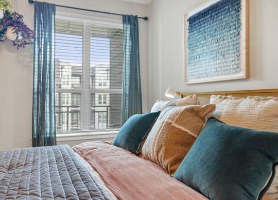 A bedroom with a large bed and a window with curtains.