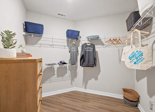 A room with a wooden cabinet and a shelf with clothes hanging on it.