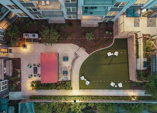 A rooftop garden with a red awning and white tables.