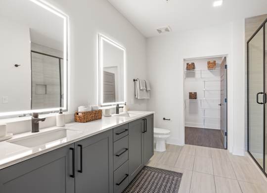 A bathroom with a white sink and grey cabinets.