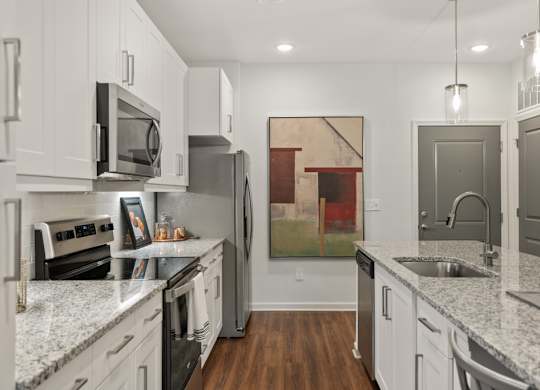 A kitchen with white cabinets and a painting hanging on the wall.