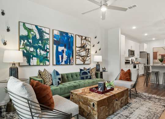 A living room with a green couch, a coffee table, and a painting on the wall.
