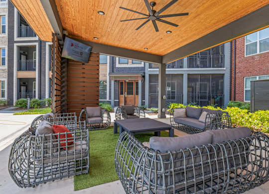 A patio with a table and chairs under a wooden roof.