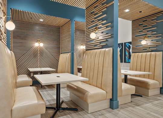 A modern dining area with a wooden slat wall and beige chairs.