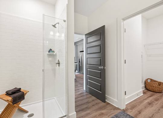 A bathroom with a walk in shower and a towel on a wooden stool.