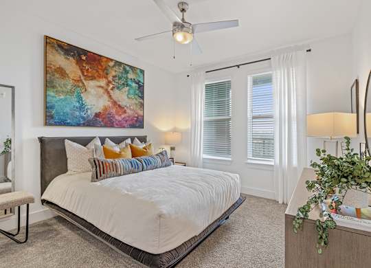 A bedroom with a large bed and a painting on the wall.