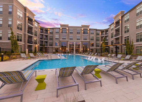 a swimming pool with chaise lounge chairs and a building in the background