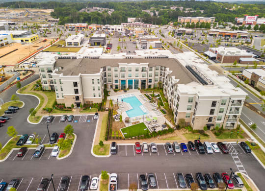 an aerial view of a large apartment complex with a pool in the middle of the parking lot