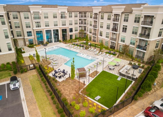 an aerial view of the resort style pool with chaise lounge chairs and grassy area