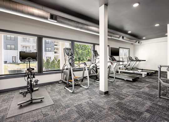 A gym with a variety of equipment including treadmills, stationary bikes, and weight machines.