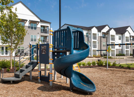 a playground with a blue slide at an apartment complex