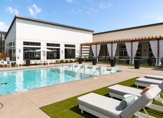 a swimming pool and lounge chairs in front of a building