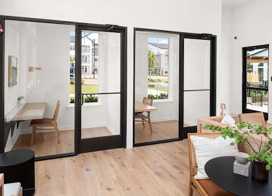 A black table with a plant on it sits in front of a glass door.
