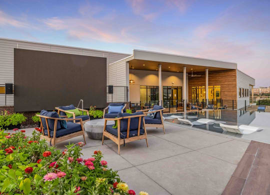 a patio with chairs and a pool in front of a building