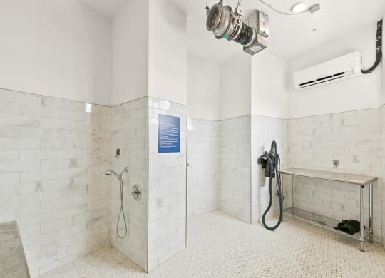 a large white tiled bathroom with a shower and a sink