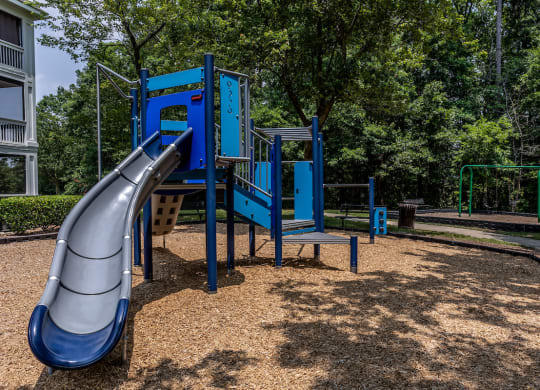 a blue playground with a slide in the middle of a park