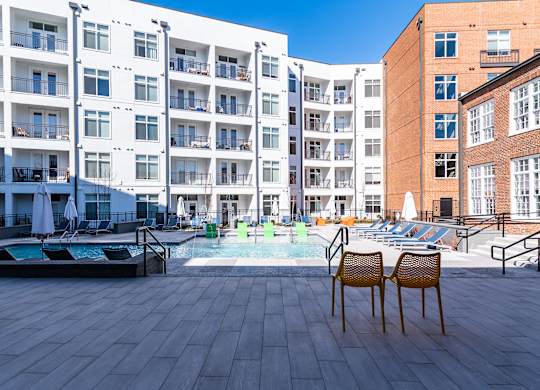 a swimming pool with chairs in front of an apartment building