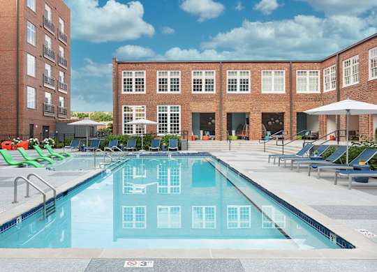 a swimming pool with lounge chairs in front of a building