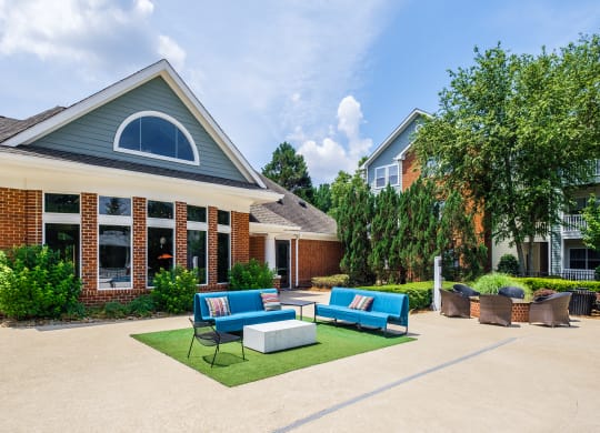 a yard with couches and chairs in front of a house