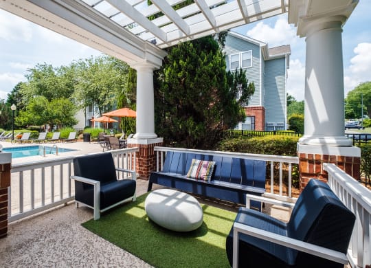 a covered patio with couches and chairs near a pool