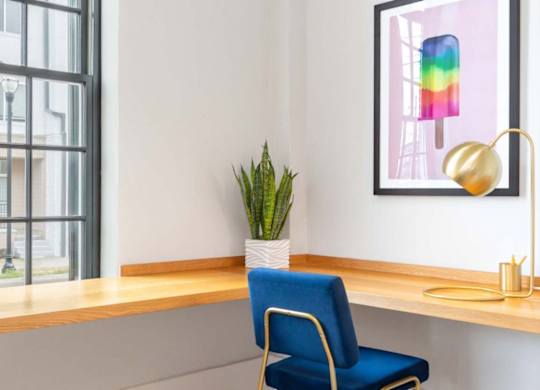 a desk with a chair and a potted plant in a room with a window