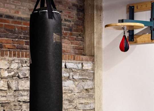 a punching bag hanging from a brick wall next to a punching ball on a rack