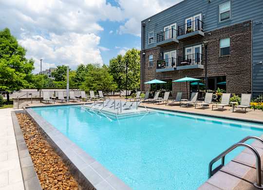 A large swimming pool surrounded by lounge chairs and umbrellas.