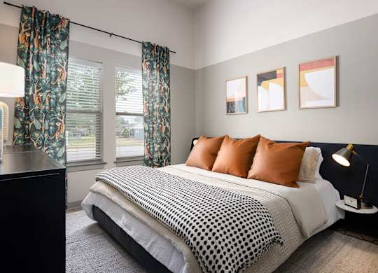 A bedroom with a bed, pillows, and pictures on the wall.