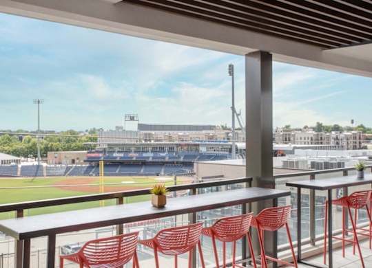 a view of a baseball stadium from a balcony with tables and chairs