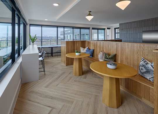 A modern dining area with wooden furniture and a view of the city.