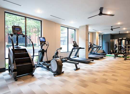 a gym with treadmills and other exercise equipment on a wooden floor