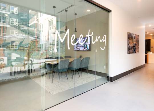 a meeting room with glass walls and a table and chairs