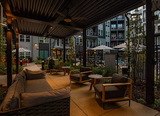 a patio with a couch and chairs and tables in front of an apartment building