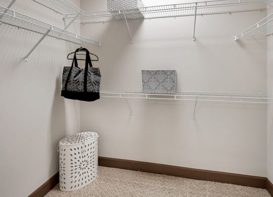 a walk in closet with a basket and bags hanging on a rack