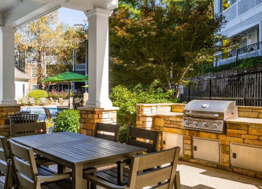 a patio with a table and chairs and a grill