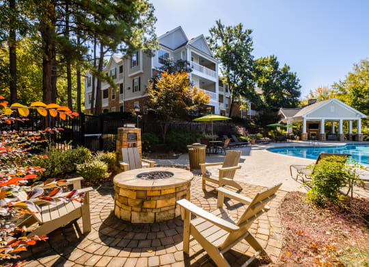 a backyard with a pool and patio with chairs and umbrellas