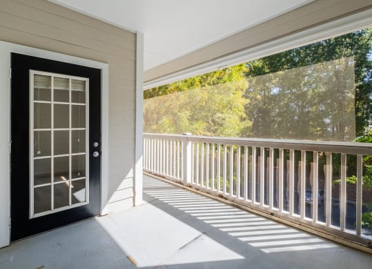 the front porch of a home with a black door and white railing