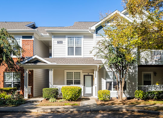 an apartment building with a porch and a tree in front of it