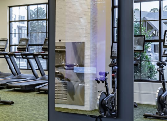 a glass wall with a reflection of a gym mirror in a gym with exercise equipment