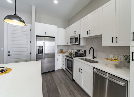 a large kitchen with white cabinets and stainless steel appliances