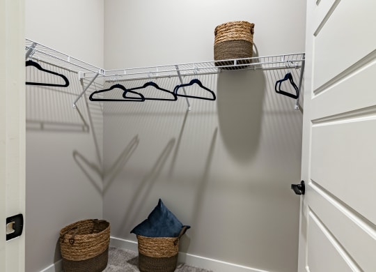the walk in closet in a new home with white walls and carpet