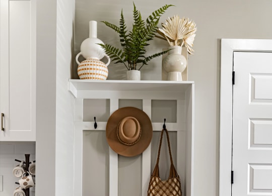 a white shelf with baskets and a hat and a purse on it