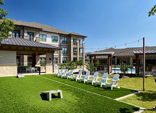 A sunny day at a resort with a row of lounge chairs and a building in the background.
