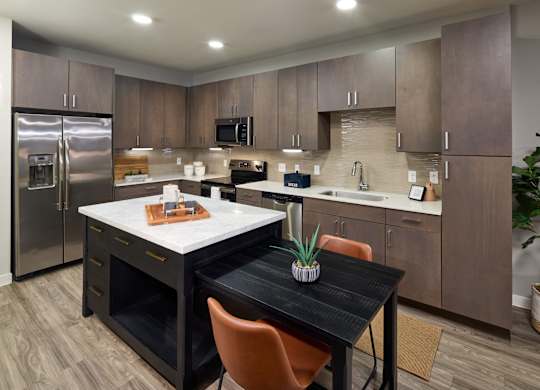 A kitchen with a table and chairs in the middle.