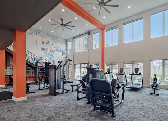 A gym with a variety of equipment including treadmills, weights, and exercise machines.
