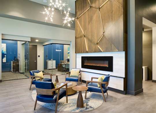 A modern living room with a fireplace and blue chairs.